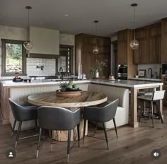 a large kitchen with wooden floors and an island in the center surrounded by gray chairs