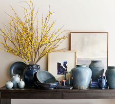 a table with vases, plates and pictures on it in front of a bench