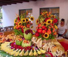 two vases filled with flowers on top of a table covered in fruits and vegetables