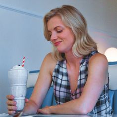 a woman sitting at a table with a drink in her hand