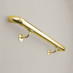 a gold coat hook with two hooks on the side and one is attached to a wall