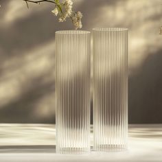 two tall glass vases sitting next to each other on a table with flowers in it