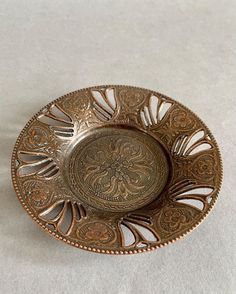 an ornately designed metal dish on a white tablecloth, with no one around it