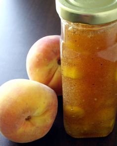 two peaches sitting next to a glass jar filled with liquid