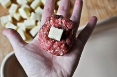 a hand holding a piece of food in it's palm next to some cheese cubes