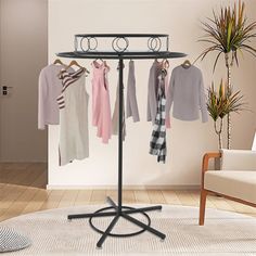 a rack with clothes hanging on it in front of a chair and potted plant