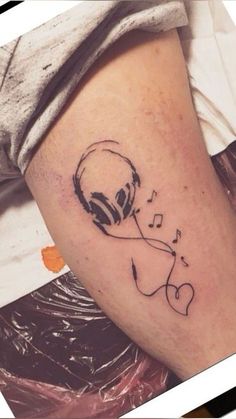 a tattoo on the leg of a person with musical notes coming out of their ear