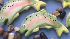 three fish shaped cookies sitting on top of some rocks and pebbles next to each other