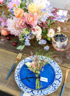 a blue and white plate with flowers on it next to a glass vase filled with water