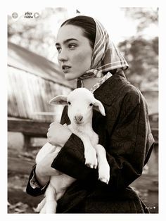 a woman holding a baby lamb in her arms