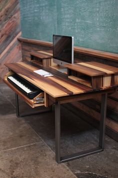 a computer desk with a keyboard and monitor on it in front of a chalkboard