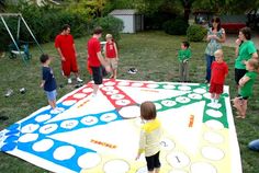 a group of people standing around a giant board game on the ground in a yard