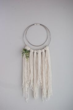 a white wall hanging on the side of a wall with two circular rings and flowers