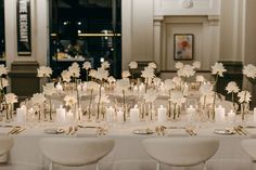 the table is set with white flowers and candles for an elegant dinner or reception party