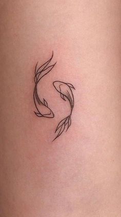 a small tattoo on the side of a woman's thigh, with two fish in it