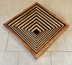 a square shaped wooden cutting board sitting on top of a tiled floor