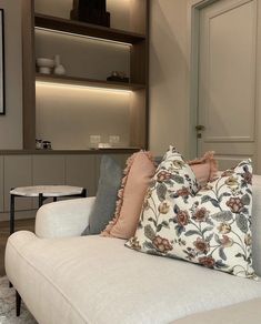 a living room with a white couch and some pillows on the back of it's chair