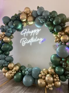 a happy birthday sign surrounded by balloons and greenery