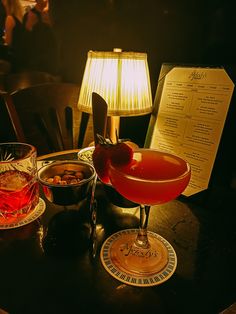 a table topped with two glasses filled with liquid and food next to a menu board