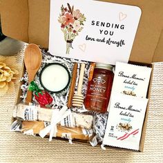 a box filled with lots of food and condiments next to a sign that says sending you love and strength