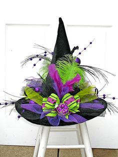 a black witch hat with purple and green feathers on top of a step stool in front of a white door