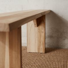 a wooden bench sitting on top of a carpeted floor next to a white wall