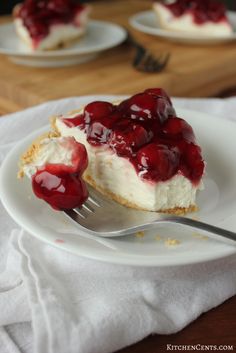 a piece of cheesecake with cherries on it and a fork in the foreground