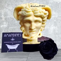 the statue is next to a black rose and card holder with an ad for amandine's