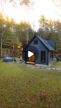 a small blue house in the middle of a wooded area with trees and grass around it