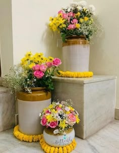 three vases with flowers are sitting on the ground