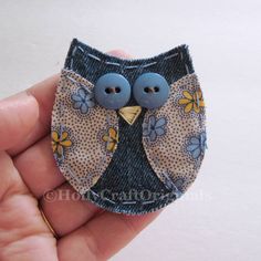 a hand holding a small blue bird brooch