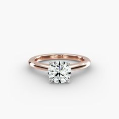 a rose gold engagement ring with a round brilliant cut diamond in the center, on a white background