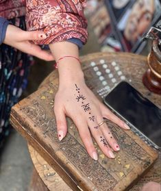 a woman's hand with a tattoo on her left wrist and fingers resting on an old wooden box