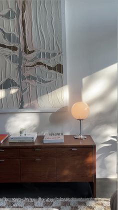 a room with a large painting on the wall and a wooden dresser in front of it