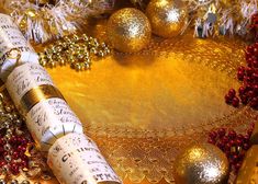 several rolls of christmas crackers sitting on top of a gold table cloth next to ornaments