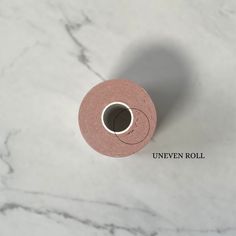 a roll of pink tape sitting on top of a white marble countertop with the words uneven roll written across it