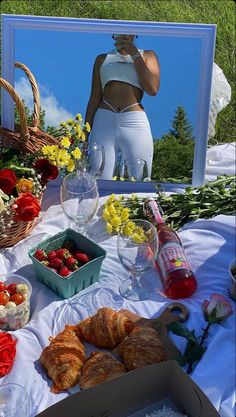 a table with flowers, croissants and wine glasses on it in front of a mirror