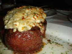 a meatball covered in cheese on top of a white plate