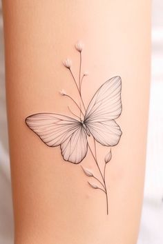 a white butterfly tattoo on the thigh with flowers in it's back side,