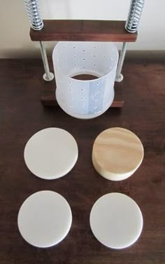 four white coasters sitting on top of a wooden table next to a blender