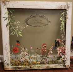 an old frame with flowers and butterflies painted on the inside is sitting on a wooden floor