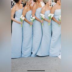 a group of women standing next to each other wearing blue dresses and holding bouquets