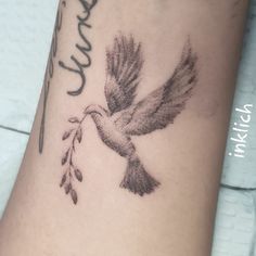 a small tattoo on the leg of a woman's arm with a bird flying above it