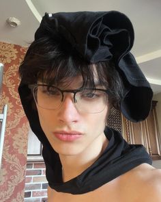 a woman with glasses and a black hat on her head is posing for the camera