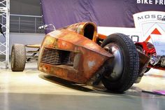 an old race car sits on the ground in front of a purple sign that says bike friday