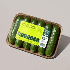 several cucumbers in a cardboard container with a label on it's side