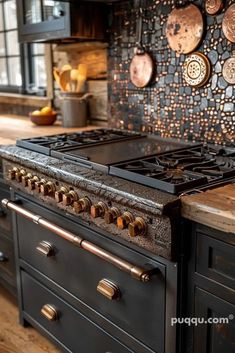 a stove top oven sitting inside of a kitchen next to an oven with copper pans on the wall