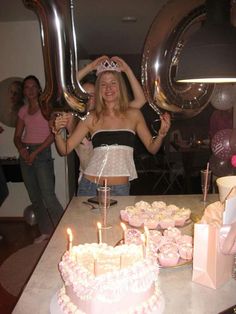 a woman standing in front of a table filled with cupcakes and cake covered cakes