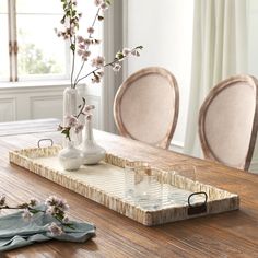 a wooden table topped with a vase filled with flowers and two glasses on top of it