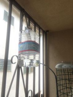 a water bottle is hanging on the side of a window sill near a trash can